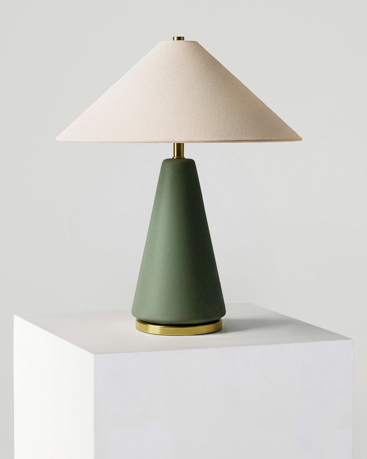Table lamp with a green base and beige shade on a white surface.