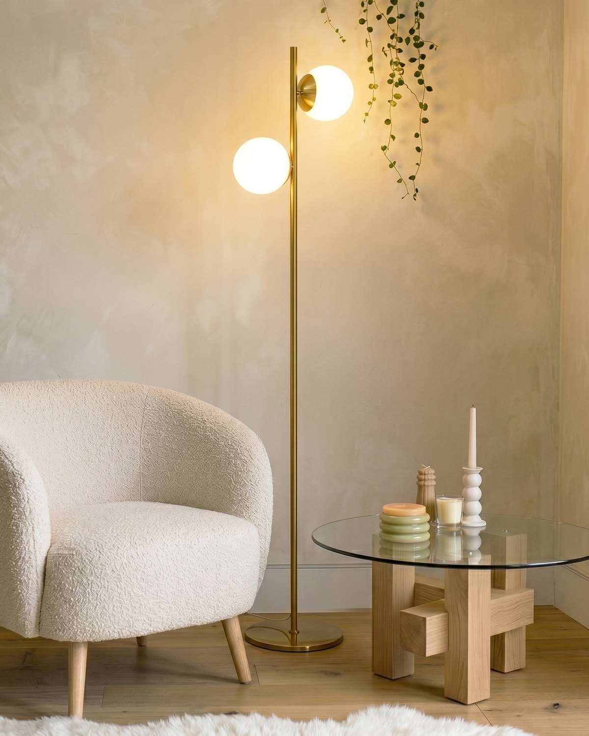 Brass Brightech Sphere floor lamp with two glowing frosted glass globes beside a boucle armchair and glass coffee table