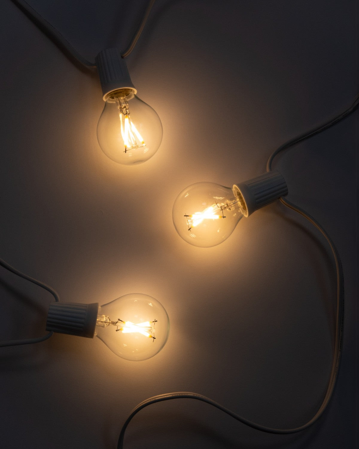Lit Brightech Ambience Globe LED string lights with white sockets glowing warm