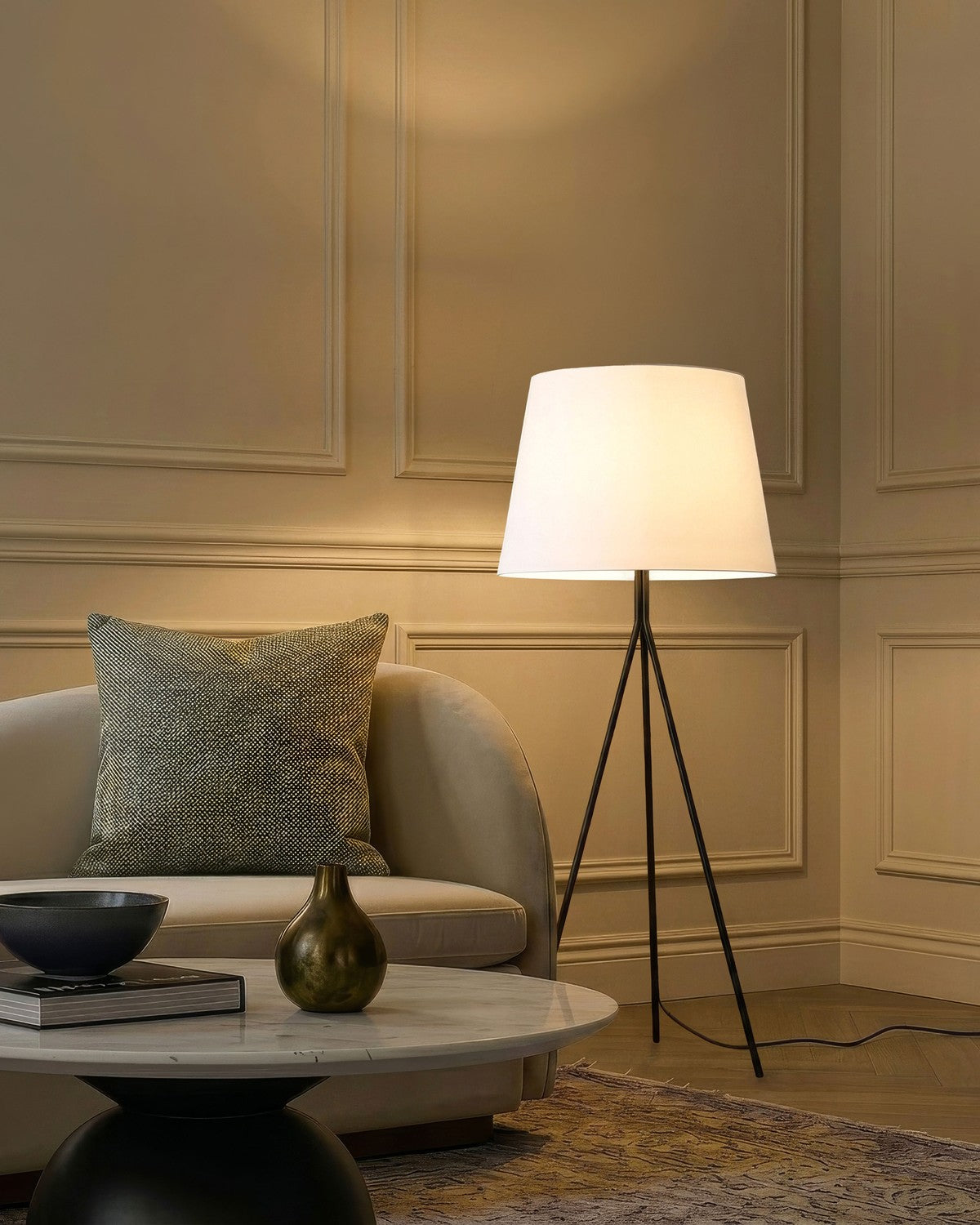 Lit Brightech Forge tripod floor lamp with a white empire shade beside a sofa in a panelled living room