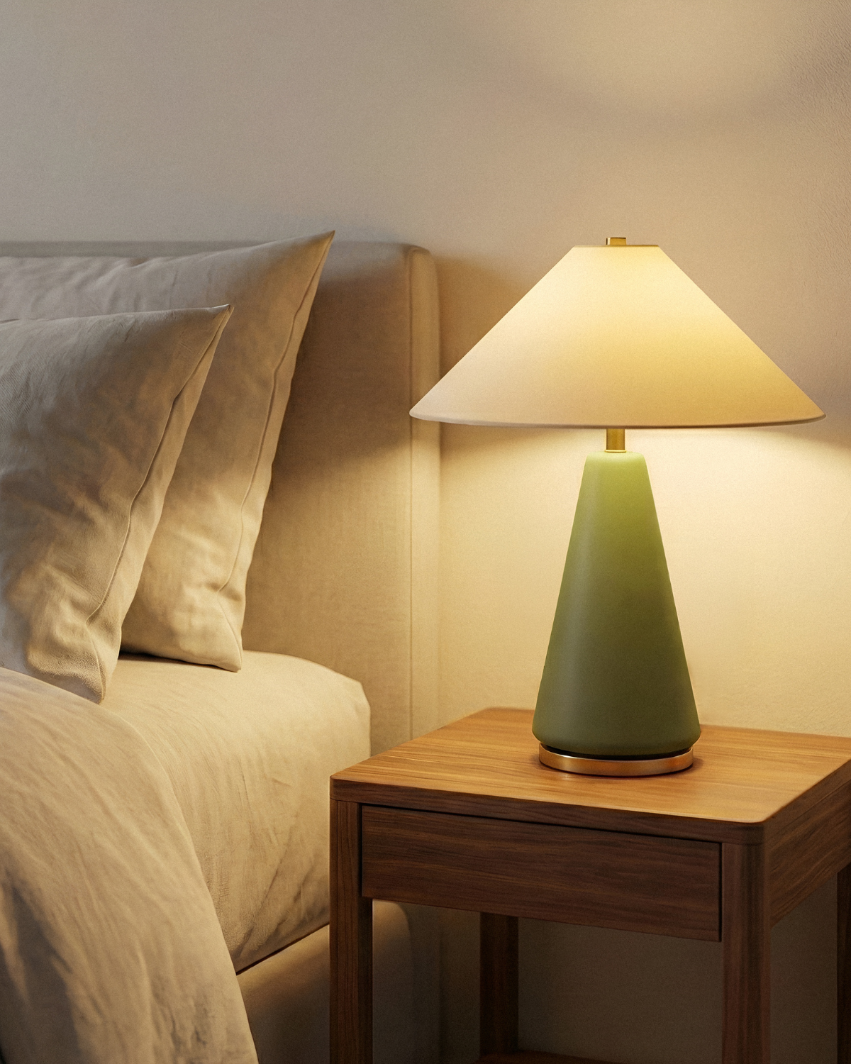 Green table lamp on a wooden nightstand next to a bed with beige bedding.
