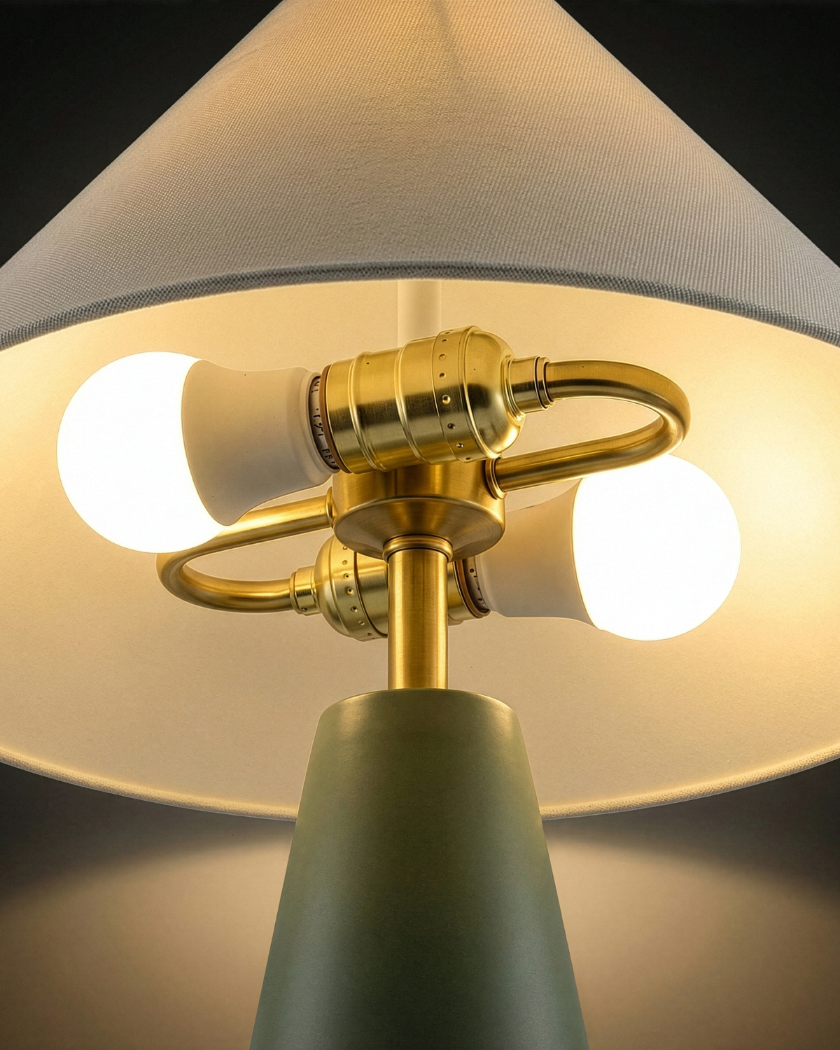 Close-up of a lamp with gold fixture and gray shade on a dark background