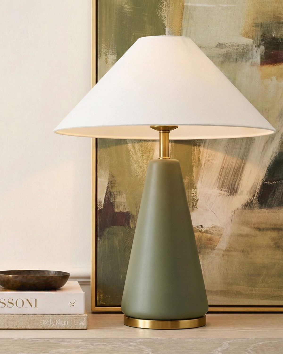 Table lamp with a green base and white shade in front of abstract art