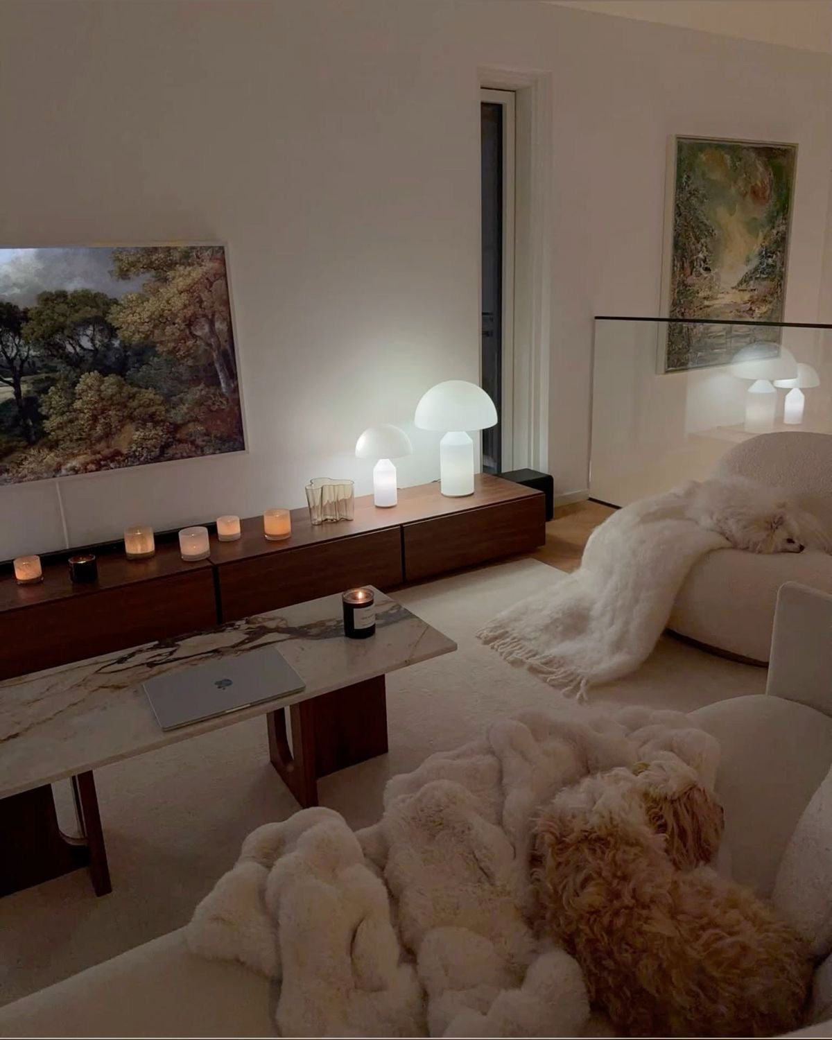 Modern living room with a dog on a couch, candles, and decorative lamps.