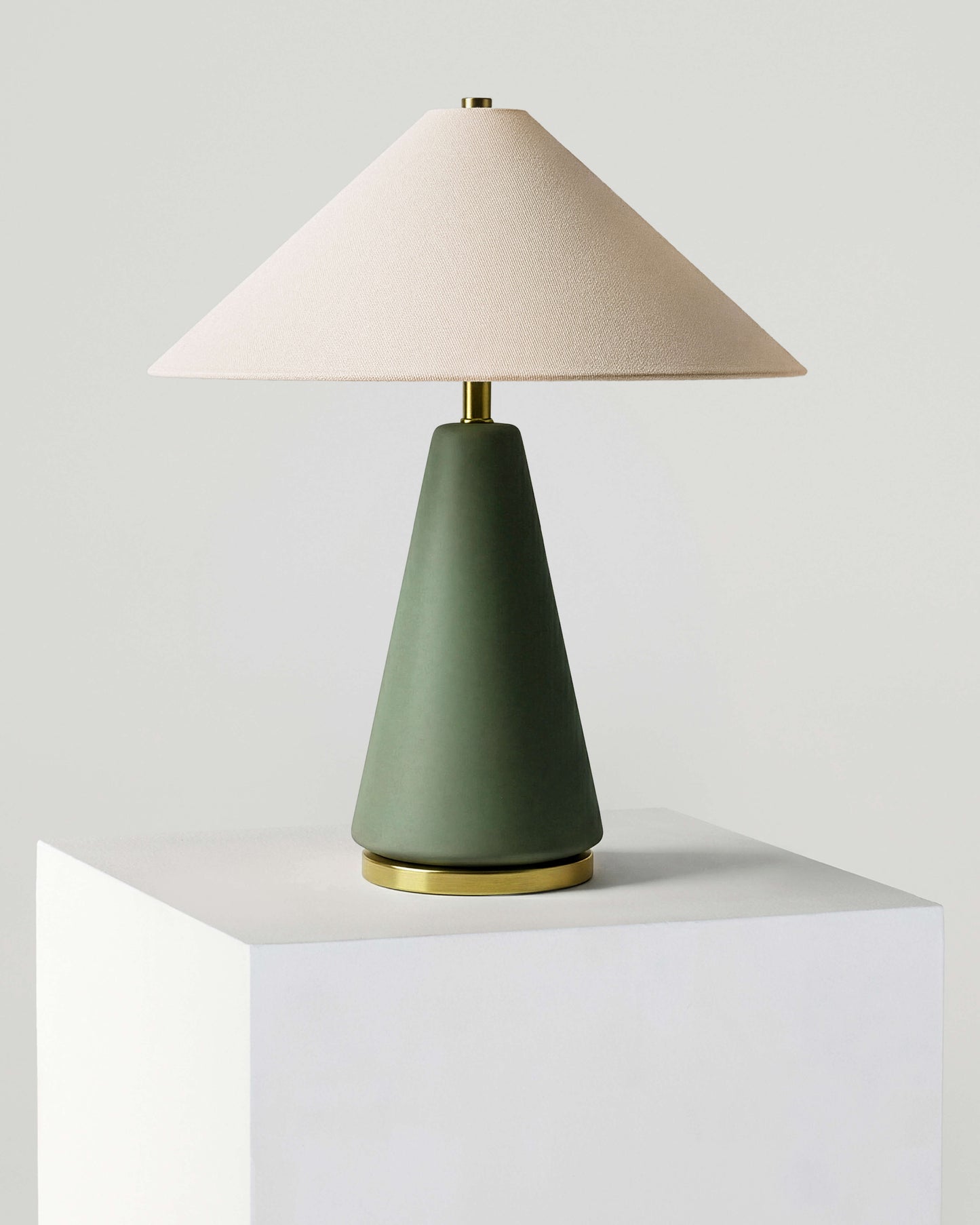 Table lamp with a green base and beige shade on a white surface.