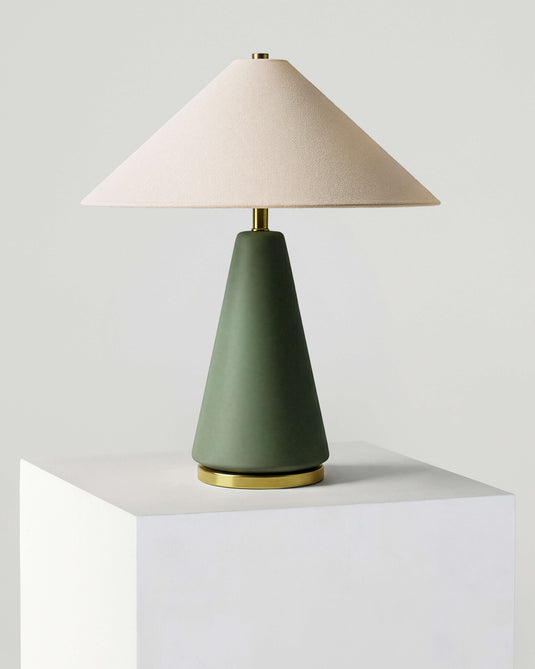 Table lamp with a green base and beige shade on a white surface.