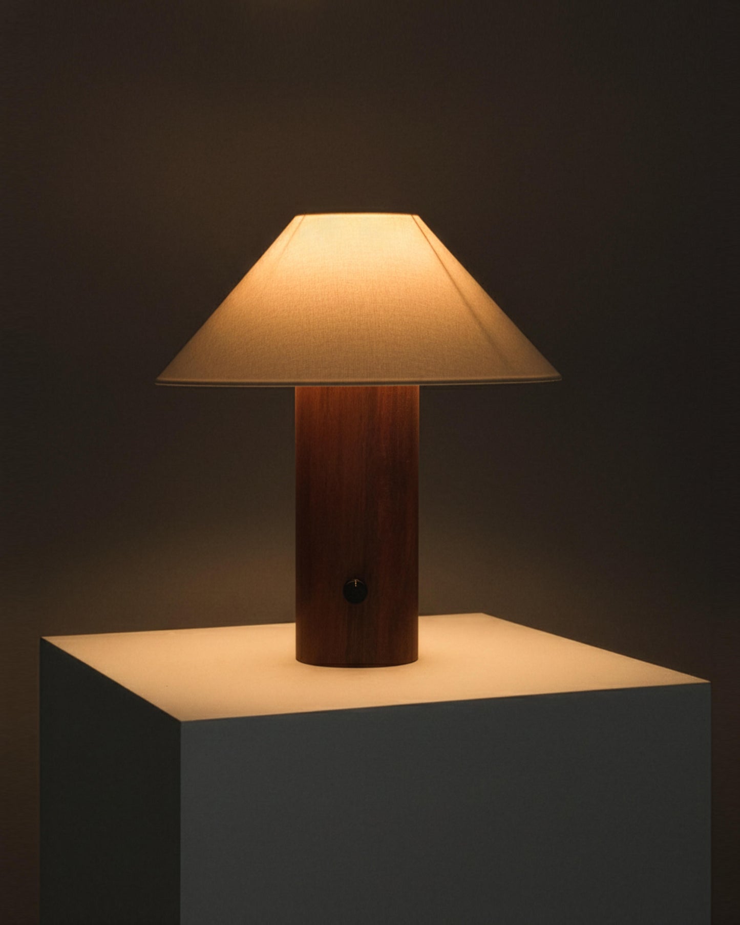 Table lamp with wooden base and beige shade on a dark background