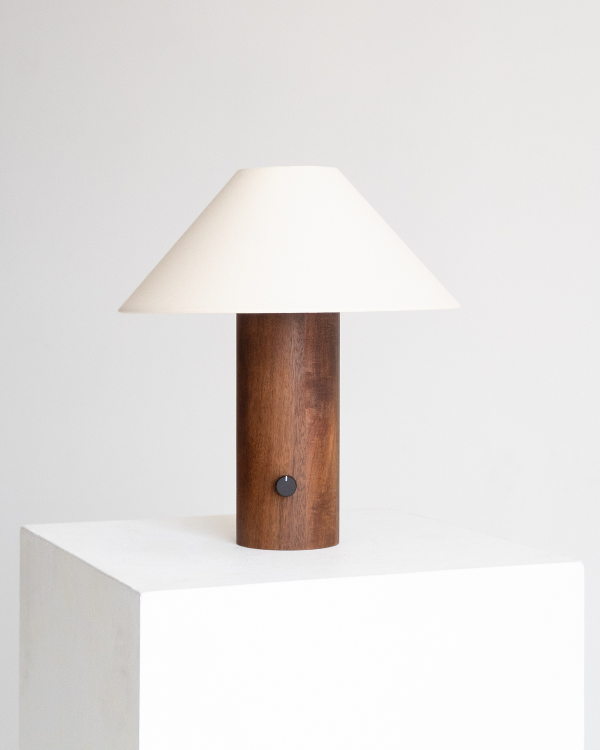 Table lamp with wooden base and white shade on a white surface