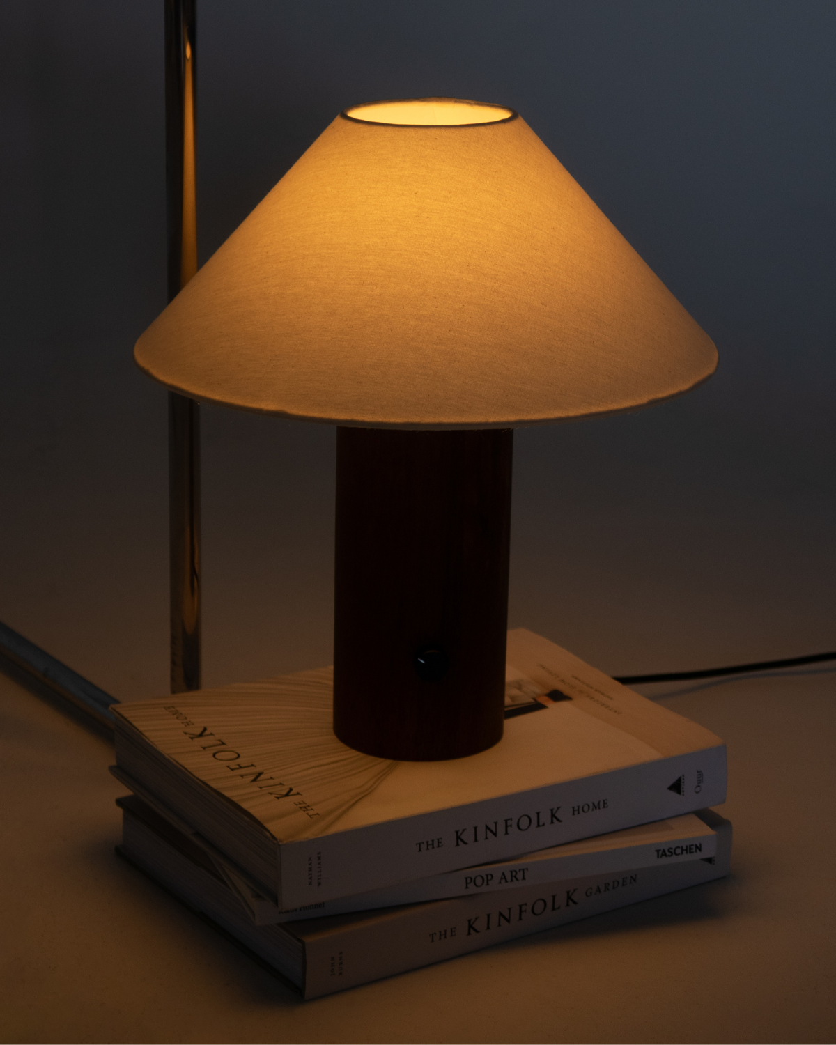 Table lamp with a fabric shade on top of books against a dark background