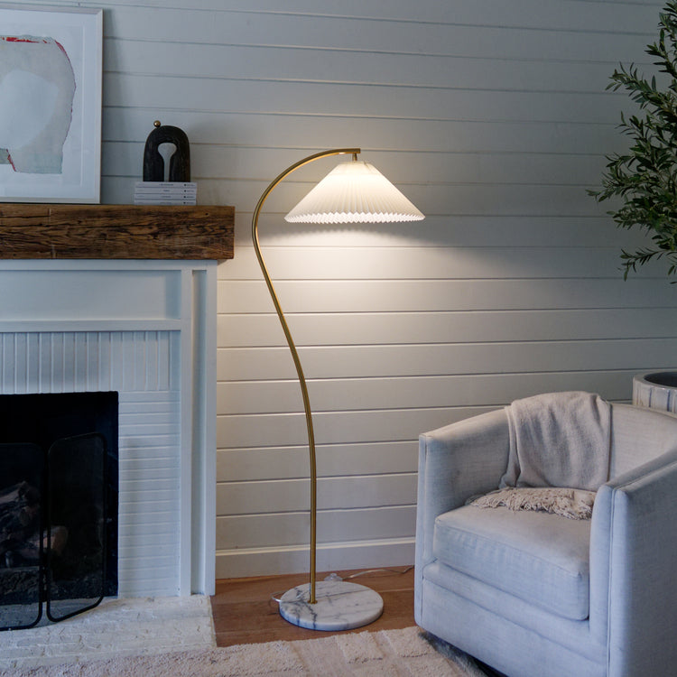 Living room with a floor lamp, armchair, and fireplace.