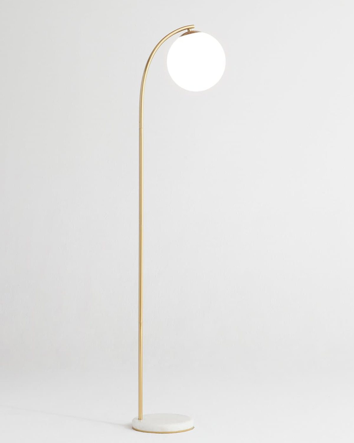 Brightech Luna Drop floor lamp with a white glass globe hanging from a brass arc over a marble base