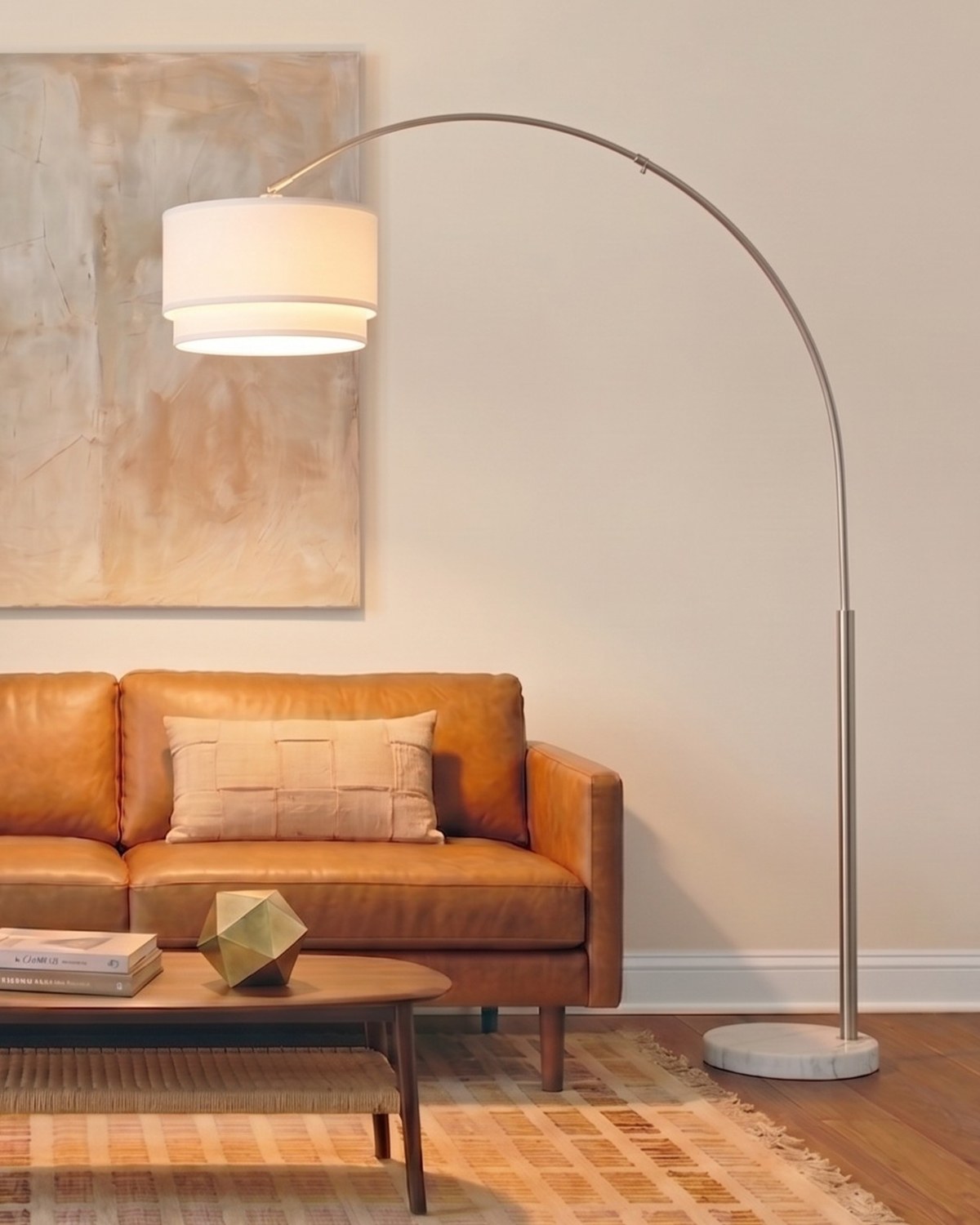 Silver Brightech Mason arc floor lamp on a white marble base arching a double drum shade over a leather sofa