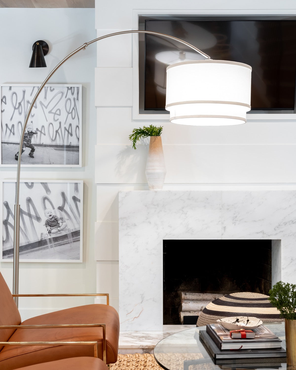 Silver Brightech Mason arc floor lamp curving its drum shade over a living room with a marble fireplace and leather chairs