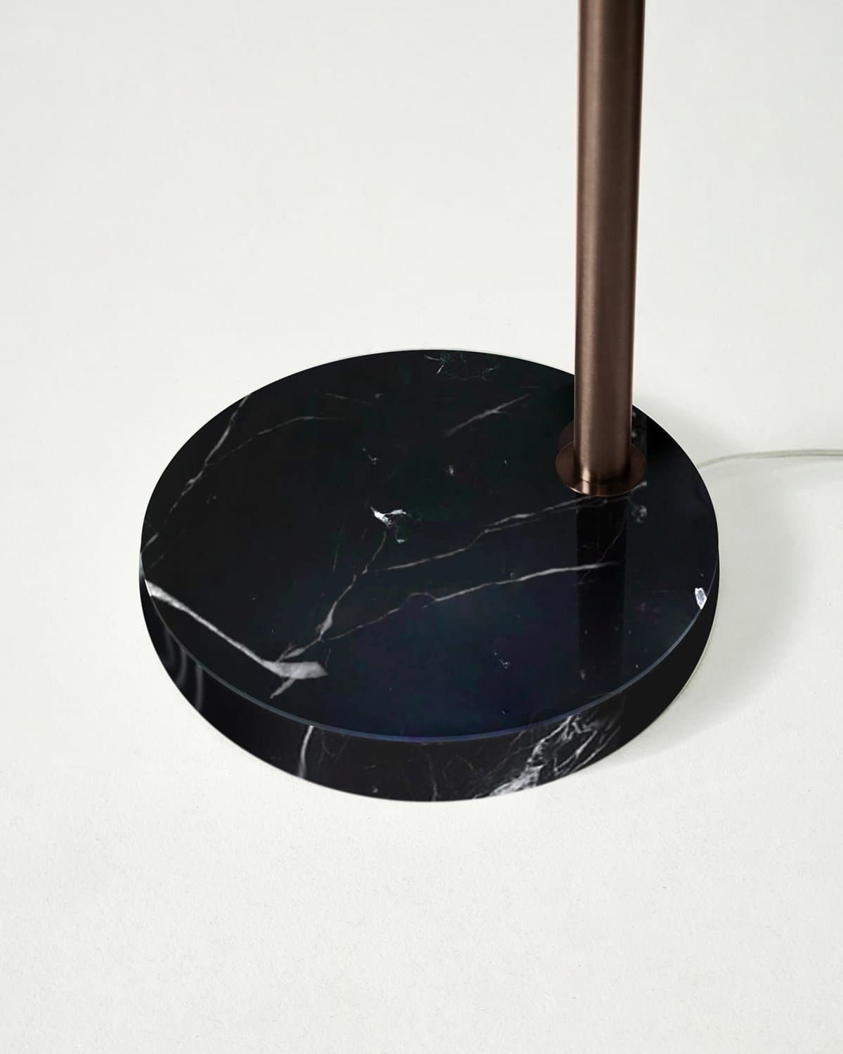 Close-up of the round black veined marble base of the Brightech Mason arc floor lamp